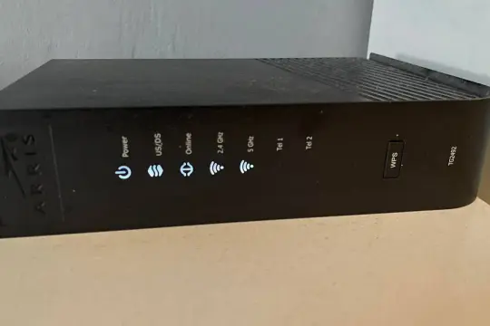 Router Arris TG2492 z przyciskiem WPS. Wskaźniki sygnalizują zasilanie, połączenie, pasma 2.4 GHz i 5 GHz, a także linie telefoniczne.
