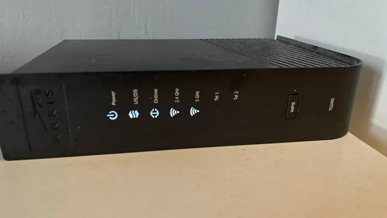 Router Arris TG2492 z przyciskiem WPS. Wskaźniki sygnalizują zasilanie, połączenie, pasma 2.4 GHz i 5 GHz, a także linie telefoniczne.